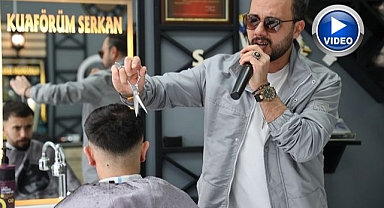 Bir elinde makas diğer elinde mikrofon 